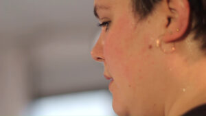 Closeup of the face of Gillie Kleiman, fat dancer, sweat glittering on her face and neck.